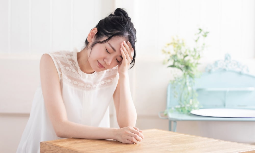頭痛でつらそうな女性
