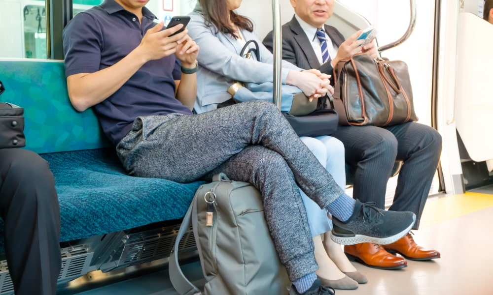 電車でスマホを見て足を組む姿勢が悪い男